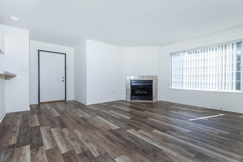 an empty living room with a fireplace and wooden floors