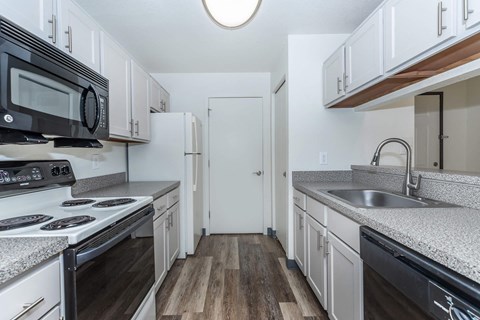 a kitchen with white cabinets and black appliances and a sink