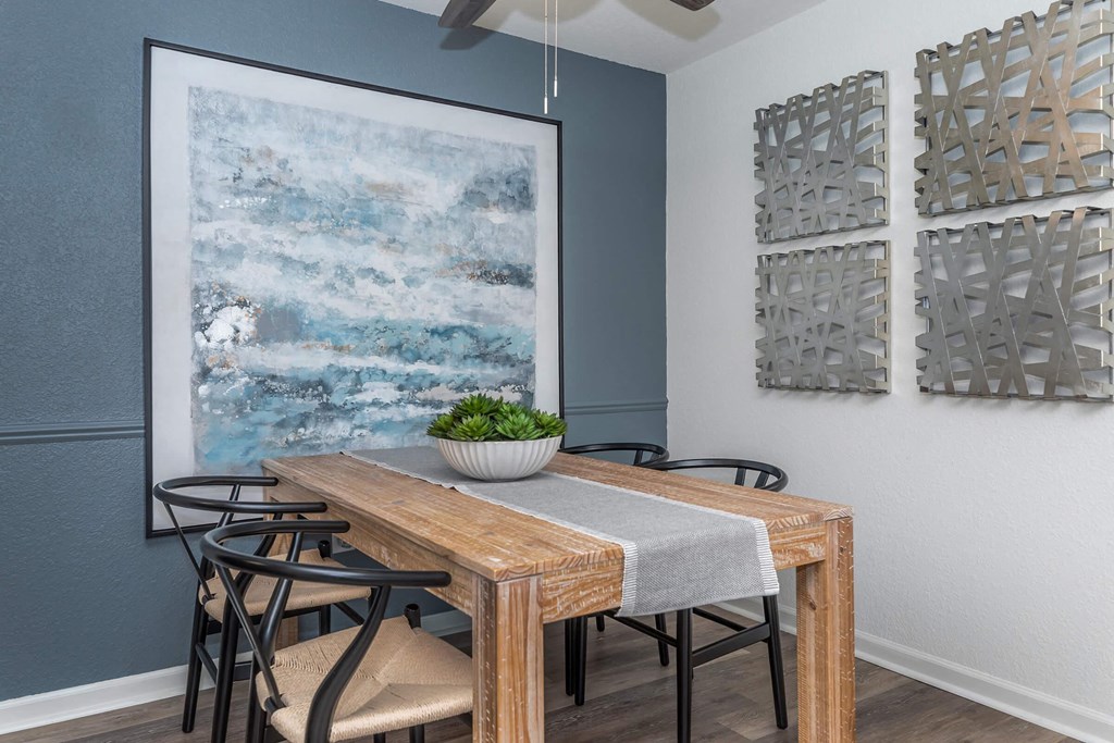 a dining room with a table and chairs and a painting on the wall