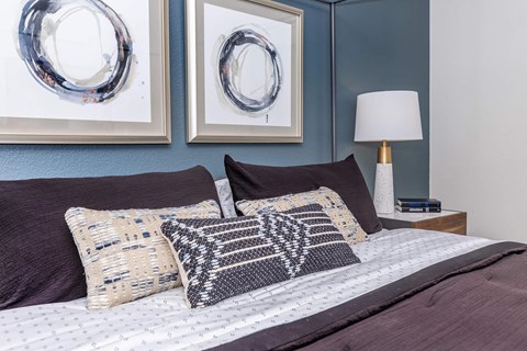 a bedroom with a bed with pillows and pictures on the wall