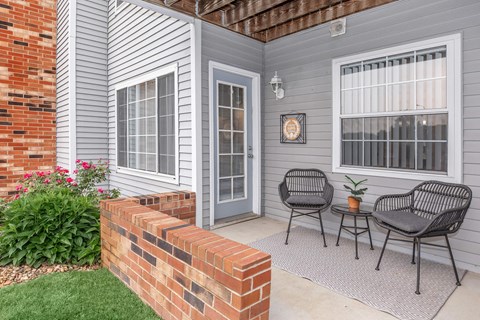 a backyard patio with two chairs and a brick wall