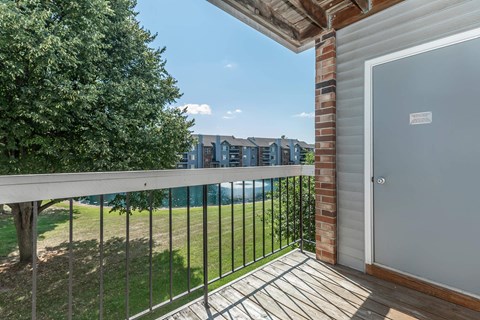 a balcony with a view of a yard and a door to a building