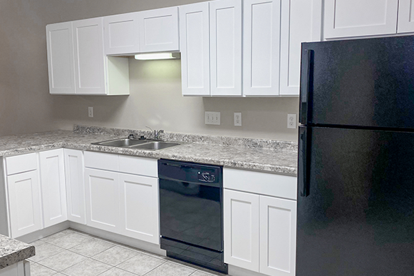 a kitchen with white cabinets and a black refrigerator