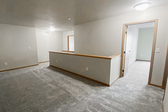 Upstairs living room in Osgood Townhome with carpet, view of two bedrooms and bathroom