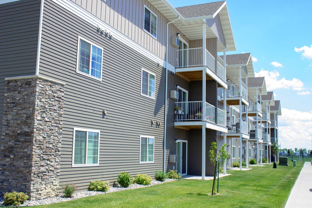 an exterior view of a building with balconies and a lawn
