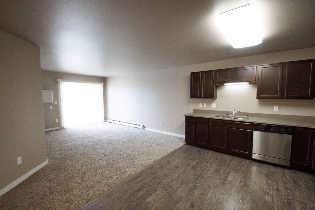 an empty kitchen and living room with wood flooring