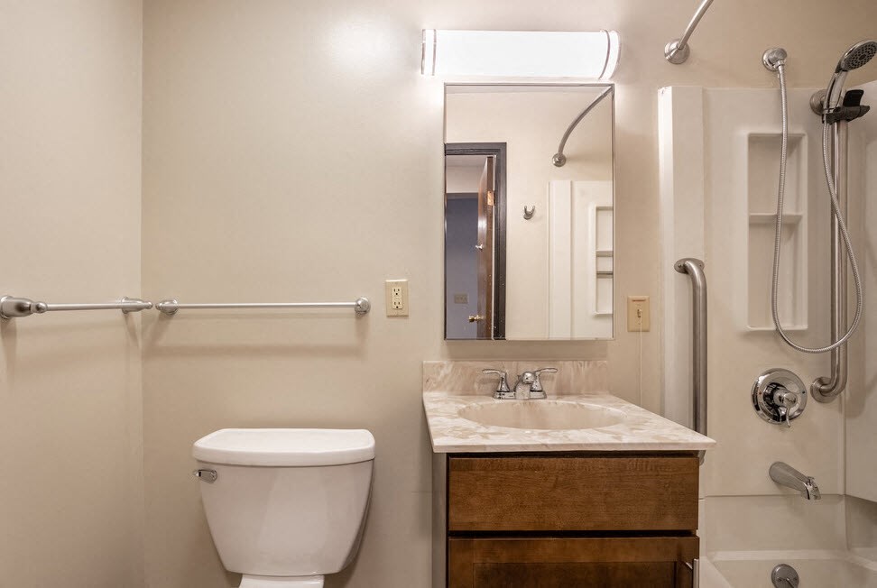 a bathroom with a toilet sink and shower and a mirror