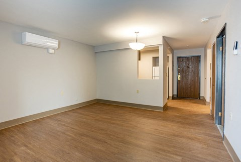 an empty living room with a wood floor and white walls