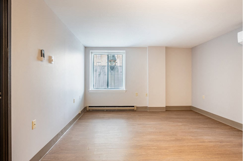 an empty room with wood floors and a window