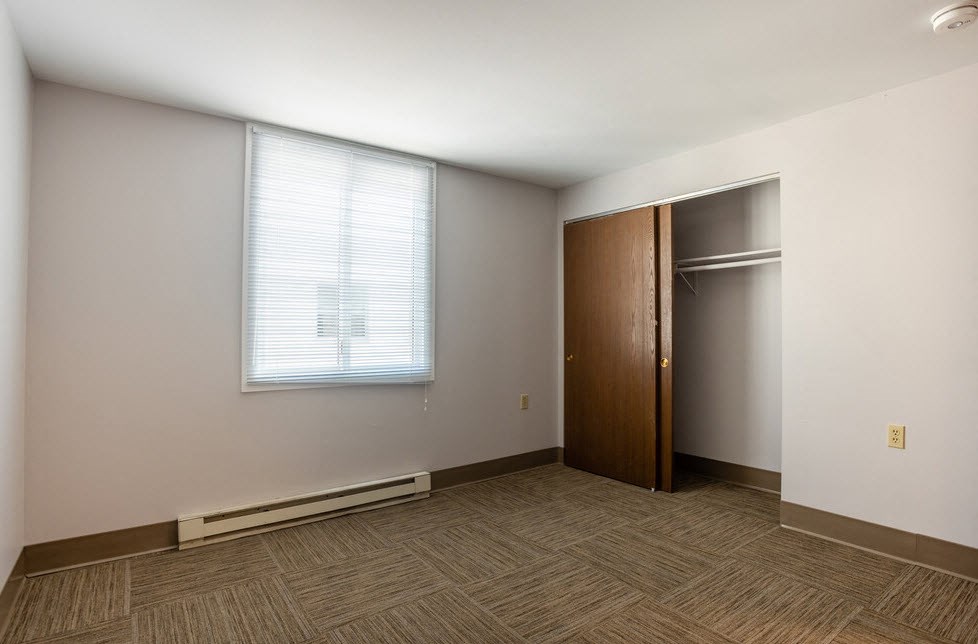 an empty room with a closet and a window