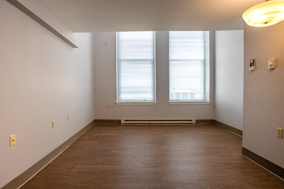 a empty room with a wood floor and three windows