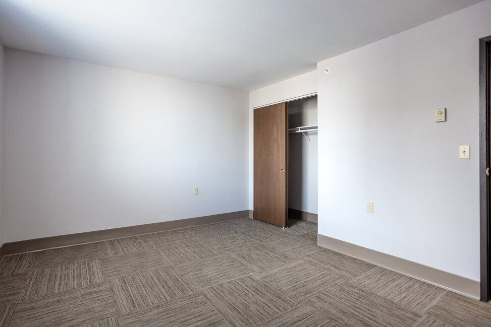 an empty living room with white walls and a door to a closet