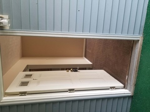 A white door is open to a cabinet.