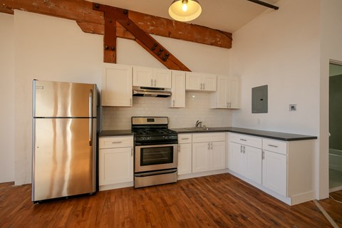 A kitchen with a stainless steel refrigerator and wooden floors.