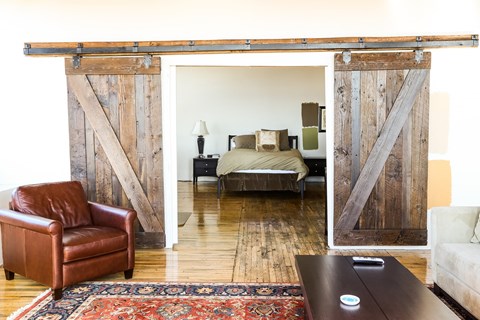 A room with a brown leather chair and a rug with a wooden wall.