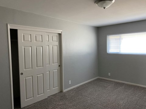 a bedroom with a door and a window and a carpeted floor