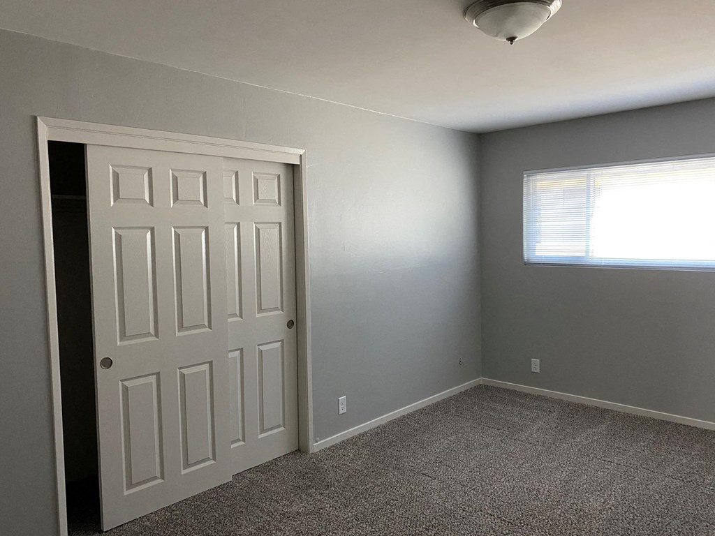 a bedroom with a door and a window and a carpeted floor
