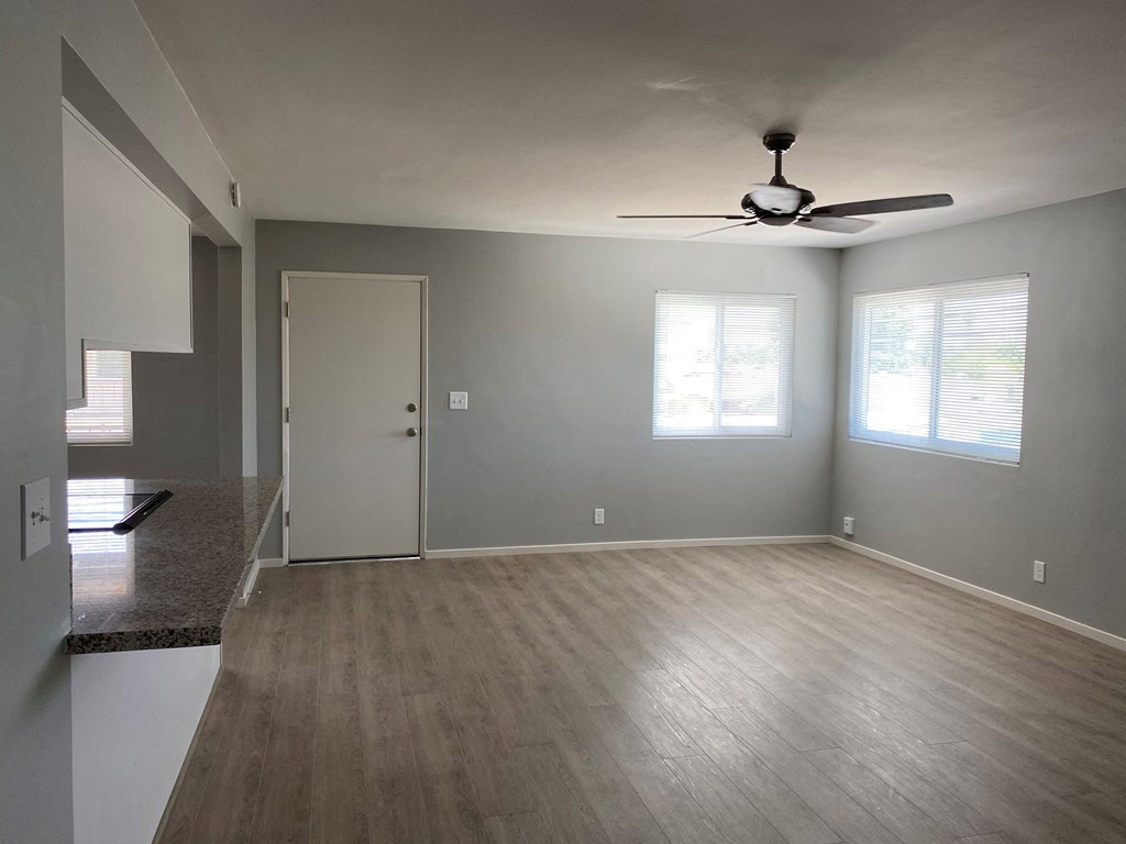 an empty living room with a ceiling fan and a door