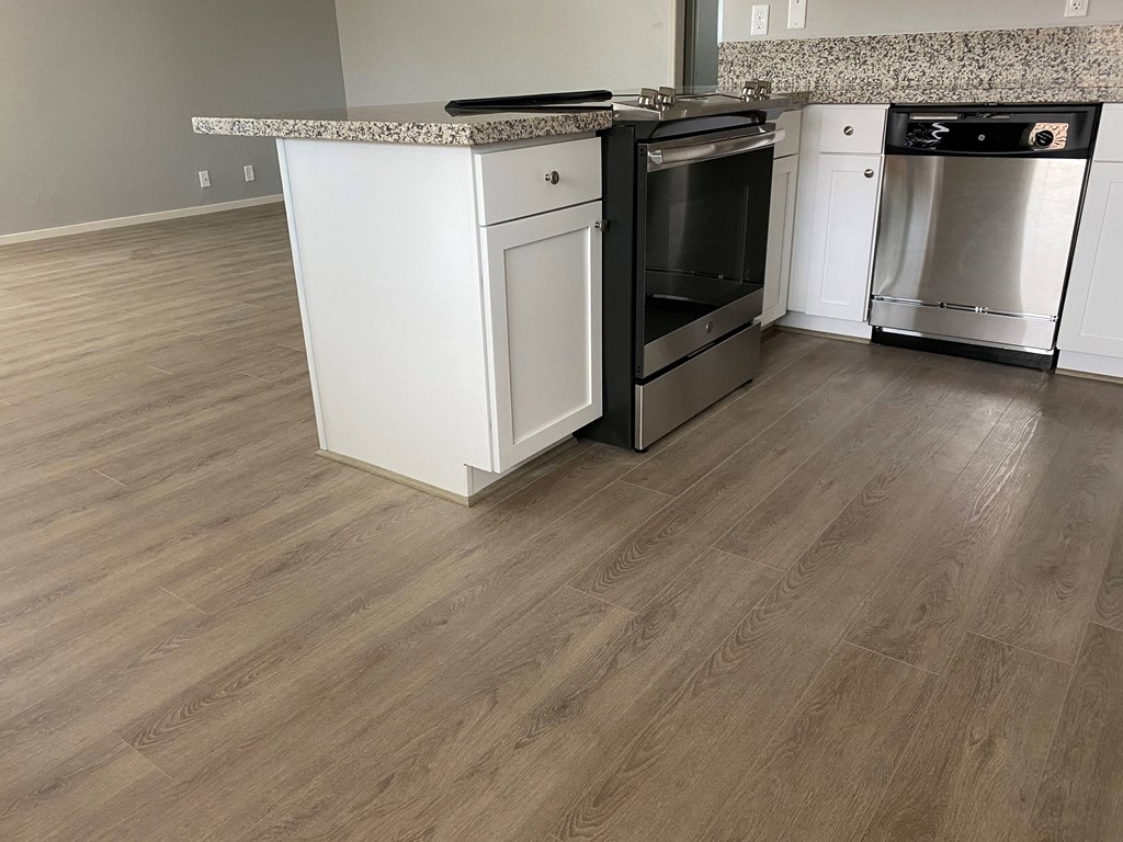 a kitchen with wood flooring and stainless steel appliances
