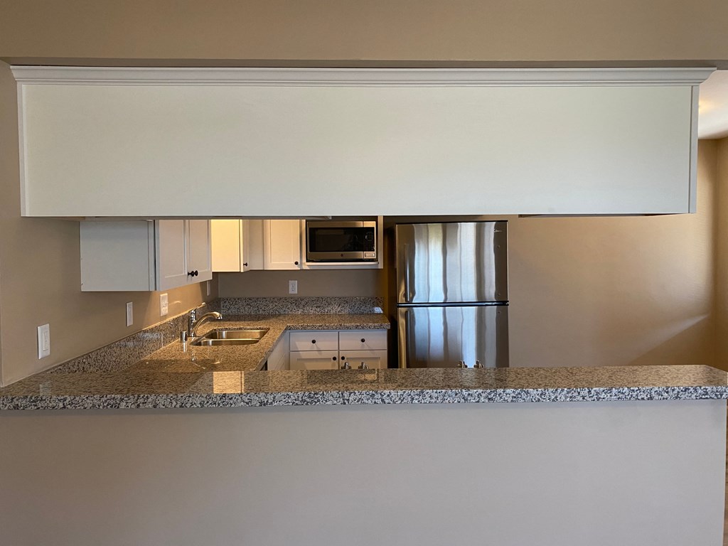 a kitchen with a granite counter top and a stainless steel refrigerator
