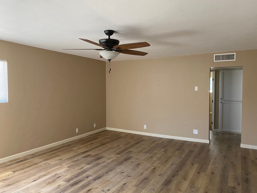 an empty living room with wooden floors and a ceiling fan