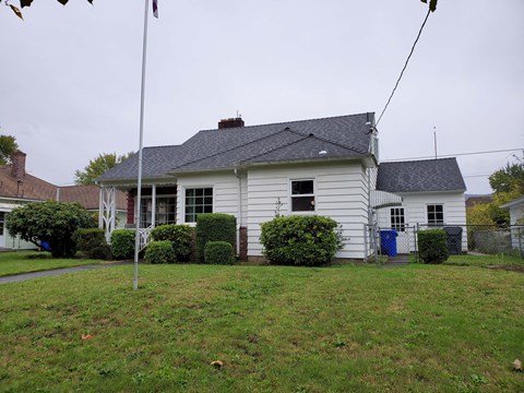 A white house with a grey roof and a blue door.
