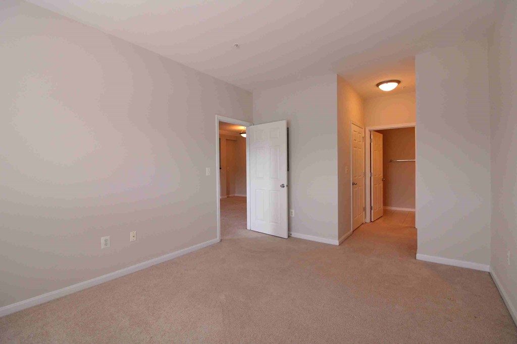 an empty living room with white walls and a door to a closet