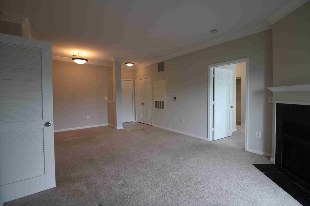 an empty living room with a fireplace and a door to a bedroom