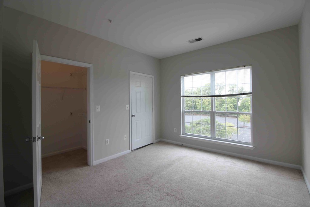 an empty bedroom with a large window and a door