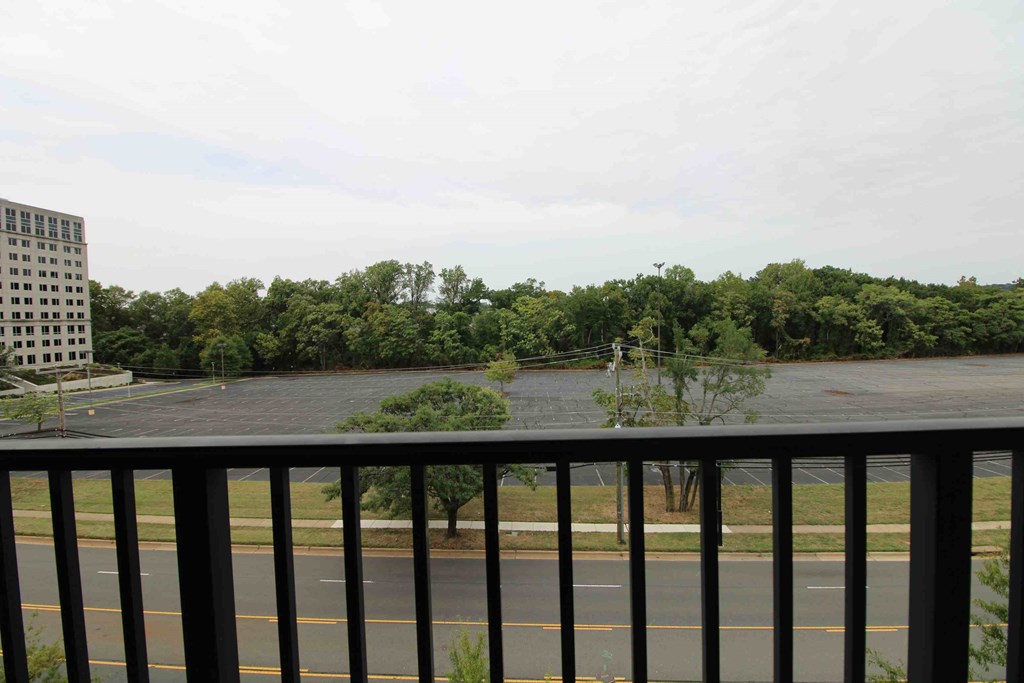 a balcony with a view of a parking lot and trees