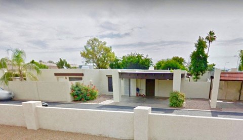 A modern house with a white fence and a car parked in front.