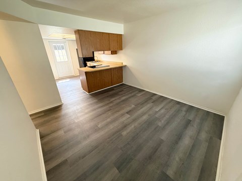A kitchen with wooden cabinets and a countertop is visible from the hallway.