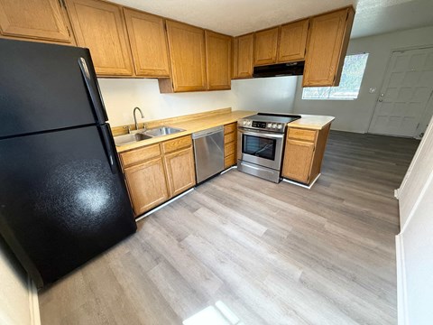 A kitchen with wooden cabinets and a black refrigerator.