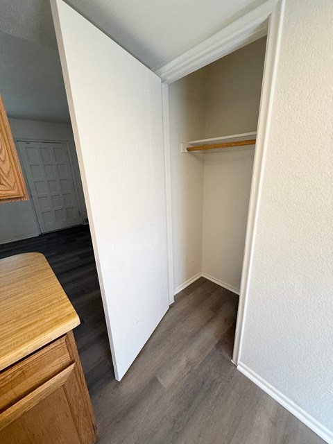 A white closet with a shelf and a white door.