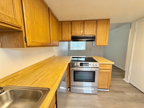 A kitchen with wooden cabinets and a stainless steel oven.