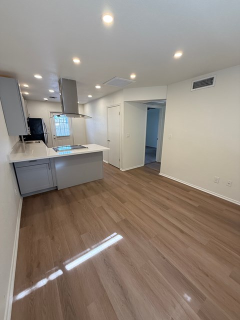 A room with wooden flooring and a kitchenette.