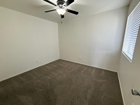 A room with a ceiling fan and carpeted floor.