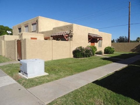 A beige house with a brown roof and a white box in front.