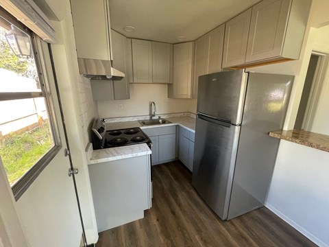 a small kitchen with white cabinets and a stainless steel refrigerator