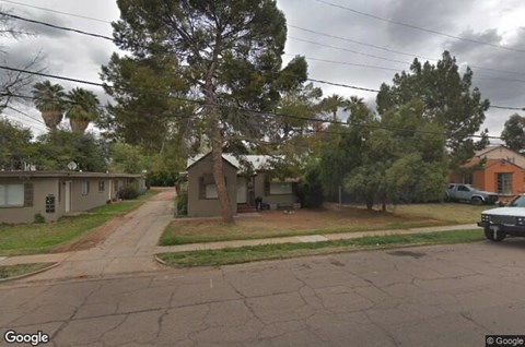 A street view of a residential area with houses and trees.