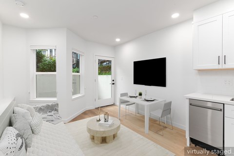 A white bedroom with a bed, a table, chairs, and a television.