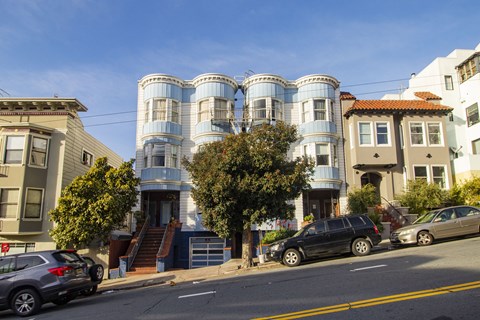 A row of houses with a car parked in front of them.