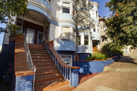 A blue and white building with a staircase leading to the front door.