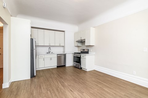 A kitchen with white cabinets and a white fridge.