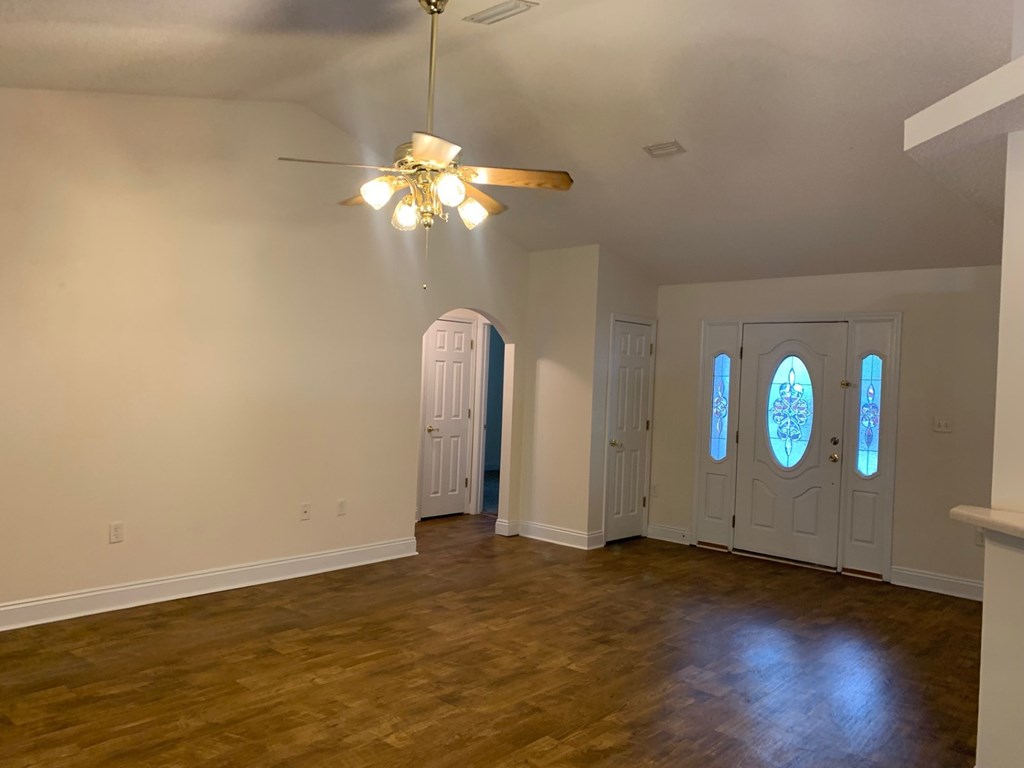 A room with a ceiling fan and three doors.