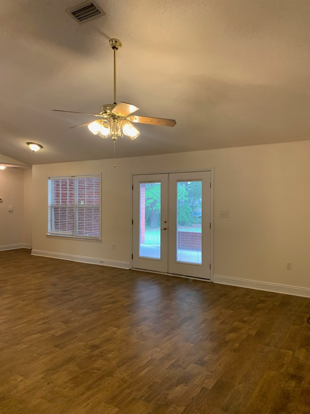 A room with a ceiling fan and sliding glass doors.