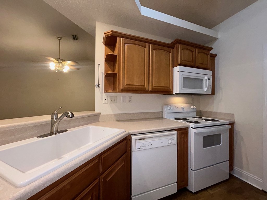 A kitchen with white appliances and wooden cabinets.