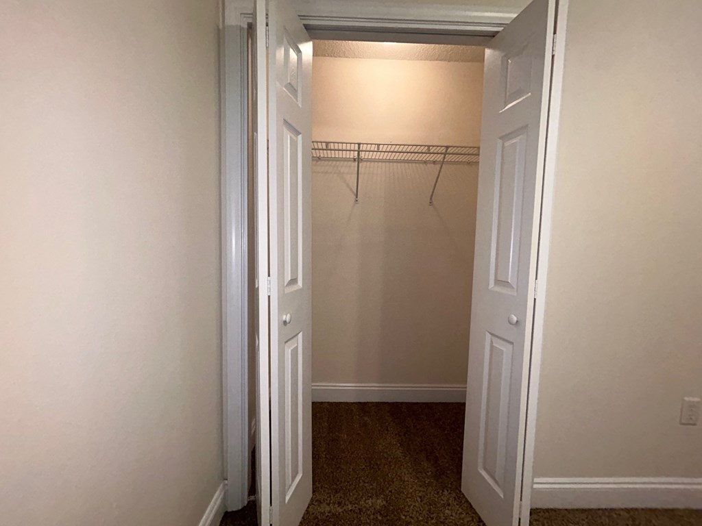 A white door is open to a room with a carpeted floor.