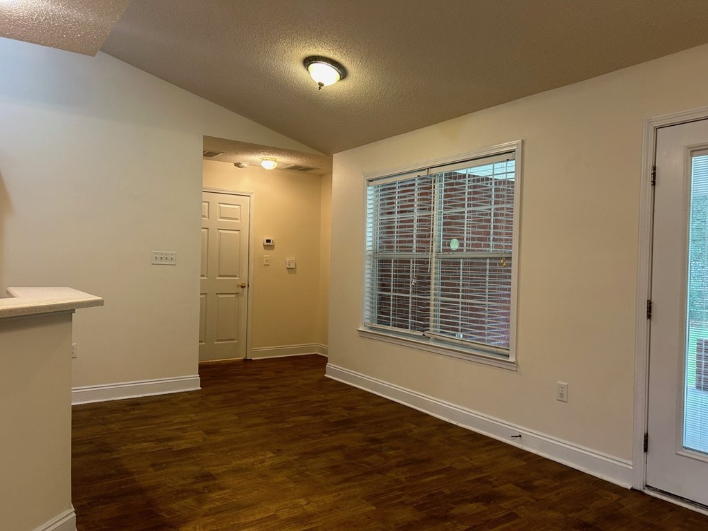 A room with a wooden floor and a window with blinds.