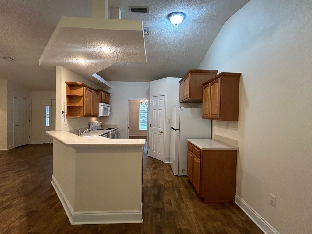 A kitchen with white walls and wooden cabinets.
